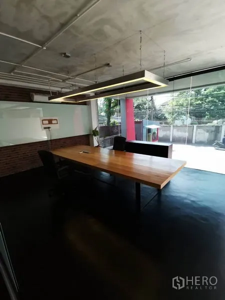 办公空间 出租在Khlong Toei, Bangkok - 会议室配大木桌与悬挂灯具，落地玻璃面向室外。