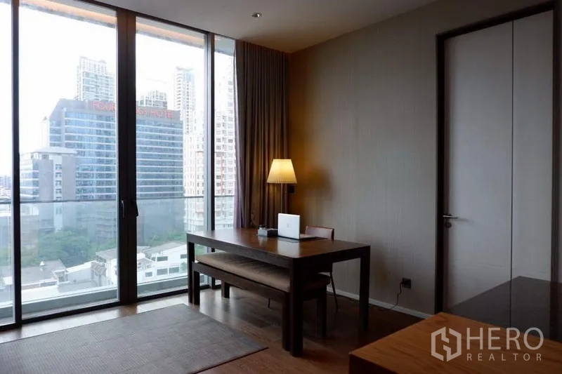 Condominium for sale in Khlong Toei, Bangkok - Dining or work nook beside full-height glass doors overlooking the Bangkok skyline.