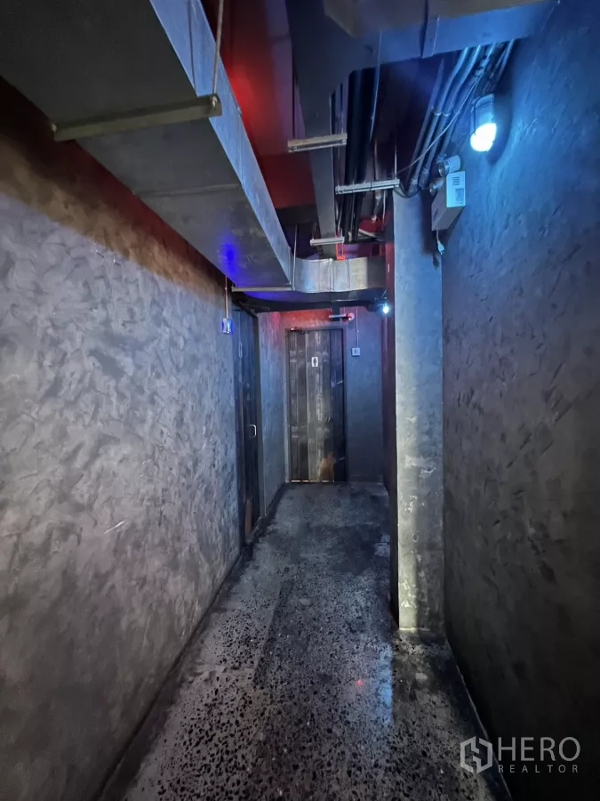 零售空间 出租 - 服务走廊，外露风管与混凝土质感墙面，通往卫生间。