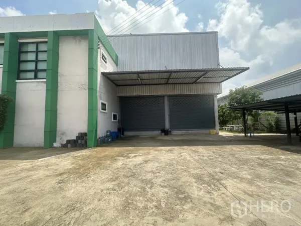 Warehouse for sale in Bang Len, Nakhon Pathom - Covered loading bay with twin roller shutter doors and a large concrete yard.