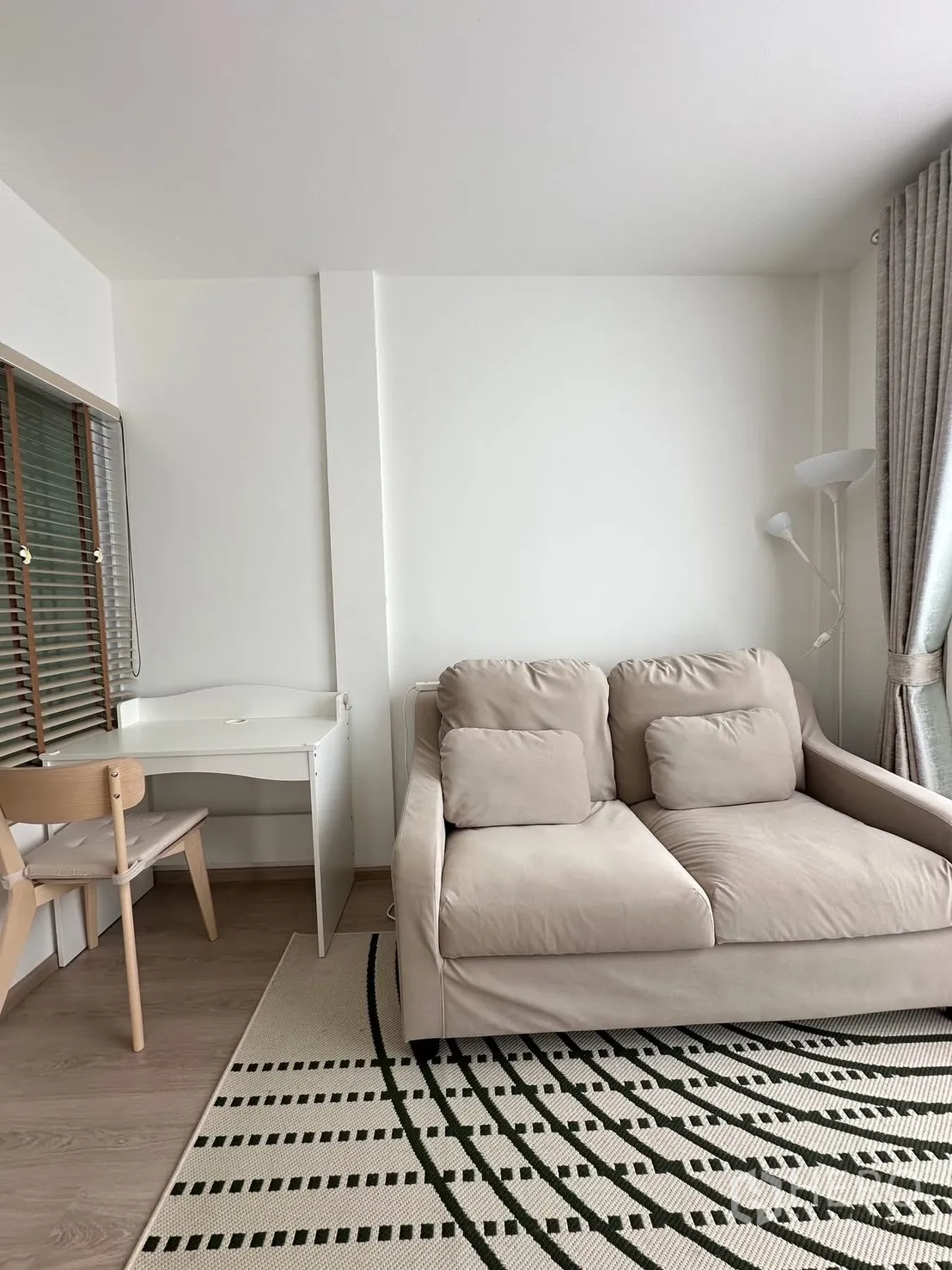 联排别墅 for rent in Prawet, Bangkok - 舒适的休闲区，米色双人沙发、书桌与落地灯。