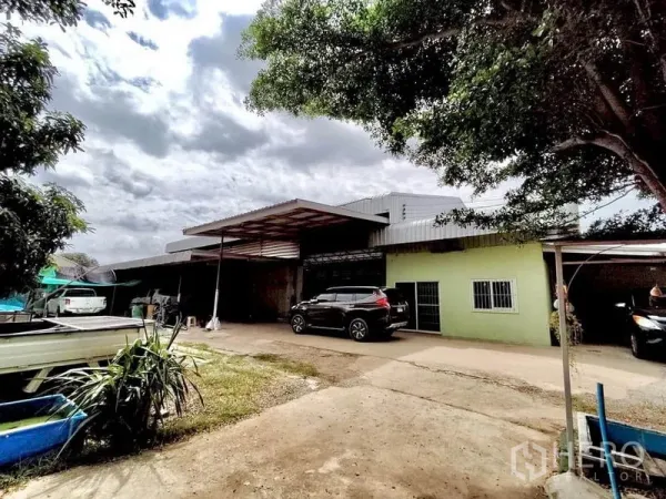 โรงงาน ขายในLat Lum Kaeo, Pathum Thani - มุมมองด้านหน้าโรงงานชั้นเดียว มีหลังคาคลุมลานขนถ่าย พื้นคอนกรีต และรถจอดใต้ร่มไม้