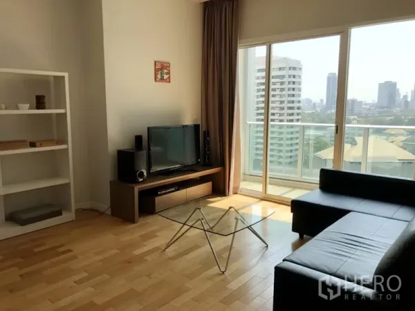 คอนโด ให้เช่าในKhlong Toei, Bangkok - ห้องนั่งเล่นสว่าง โซฟาหนังสีดำ โต๊ะกลางกระจก ชั้นวางทีวี และประตูกระจกออกสู่ระเบียงวิวเมือง