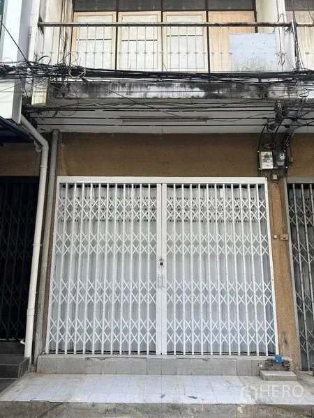 อาคารพาณิชย์ ให้เช่าในKhlong Toei, Bangkok - ด้านหน้าตึกแถวติดถนน พร้อมประตูเหล็กยืดสีขาวและระเบียงชั้นบน