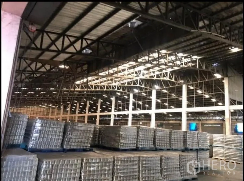 Factory for rent in Bang Khla, Chachoengsao - Close view of steel rafters and skylights above rows of pallet stacks.