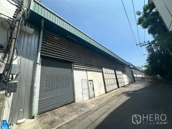Warehouse for rent in Suan Luang, Bangkok - Exterior angle of the warehouse facade with corrugated panels and a roller shutter entry.