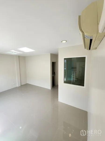 Townhouse for rent in Wang Thonglang, Bangkok - Spacious room with shiny floor tiles, an internal window and doorway to a bathroom.