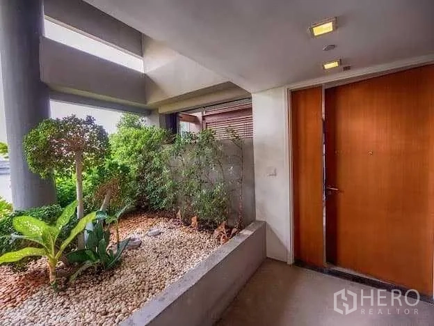 Condominium for sale in Yan Nawa, Bangkok - Private entry foyer featuring a planter garden with pebbles beside a wooden main door.