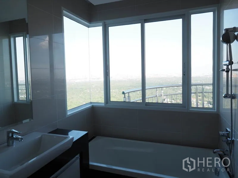 Condominium for rent or sale in Yan Nawa, Bangkok - Bathroom with bathtub and large windows offering skyline and river view.