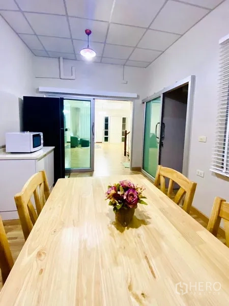 联排别墅 出租在Prawet, Bangkok - 从餐厅望向客厅的景象，带推拉玻璃门、冰箱与微波炉。