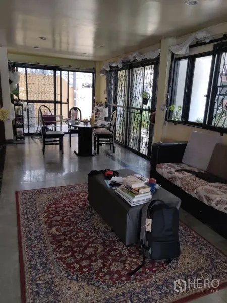 ทาวน์เฮาส์ ให้เช่าในPhra Khanong, Bangkok - พื้นที่นั่งเล่นและรับประทานอาหารยาวโปร่ง หน้าต่างหลายด้านพร้อมเหล็กดัด โซฟา และพรมลายสวย