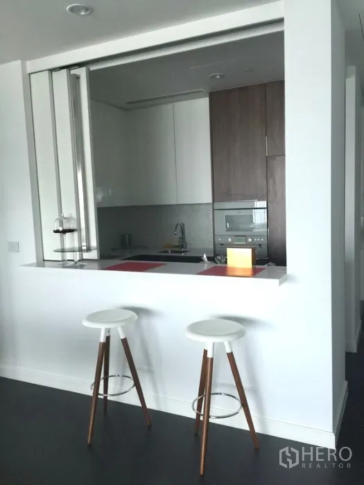 Condominium for rent or sale in Pathum Wan, Bangkok - Breakfast bar with two stools opening to the fitted kitchen