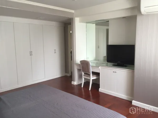 คอนโด ให้เช่าในKhlong Toei, Bangkok - ห้องนอนกว้าง ตู้เสื้อผ้าบิวต์อินสีขาว โต๊ะเครื่องแป้งพร้อมทีวี และพื้นไม้โทนอุ่น