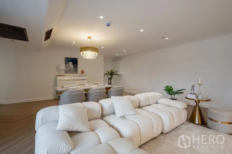 Condominium for sale in Watthana, Bangkok - Open living–dining space with a plush white sofa set and gold side tables.
