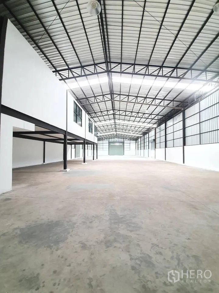 货栈 出租在Bang Khen, Bangkok - 仓库内部空间宽敞，钢桁架高顶，混凝土地面，带窗户的夹层办公区。