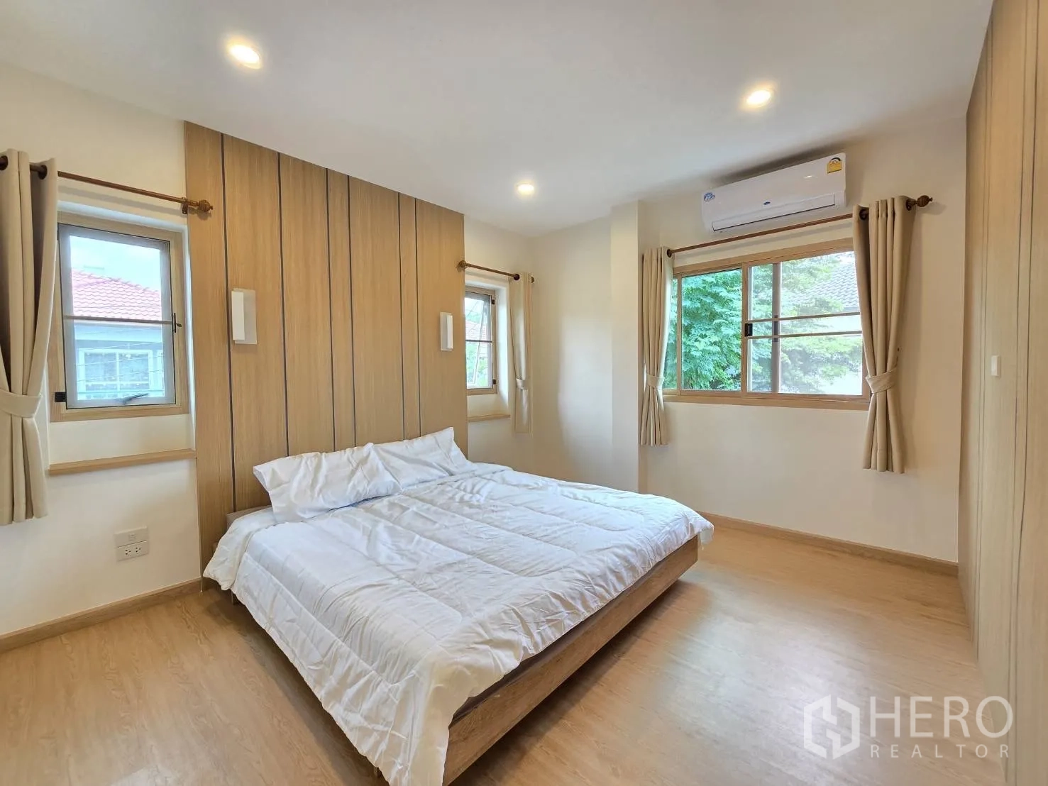 独立式住宅 出售在Suan Luang, Bangkok - 转角卧室，三面采光并配空调与木质背景墙。