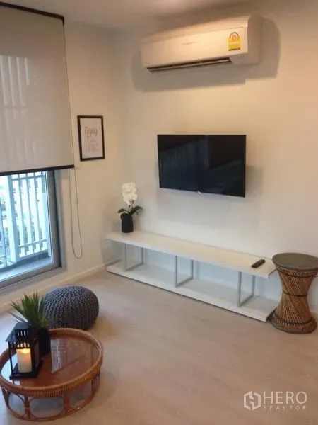 Condominium for rent in Sathon, Bangkok - TV wall with floating console, air conditioner and a window in the condo’s lounge.