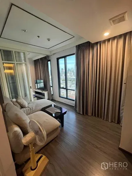 Condominium for sale in Ratchathewi, Bangkok - Living room corner with blackout curtains, wood floors and tall windows overlooking Bangkok.