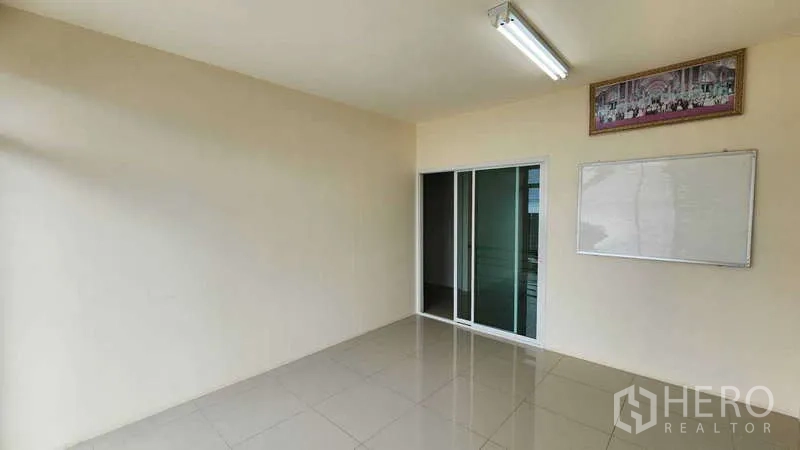 Factory for rent in Samut Sakhon - Clean office room with ceiling light, sliding doors and wall-mounted board.