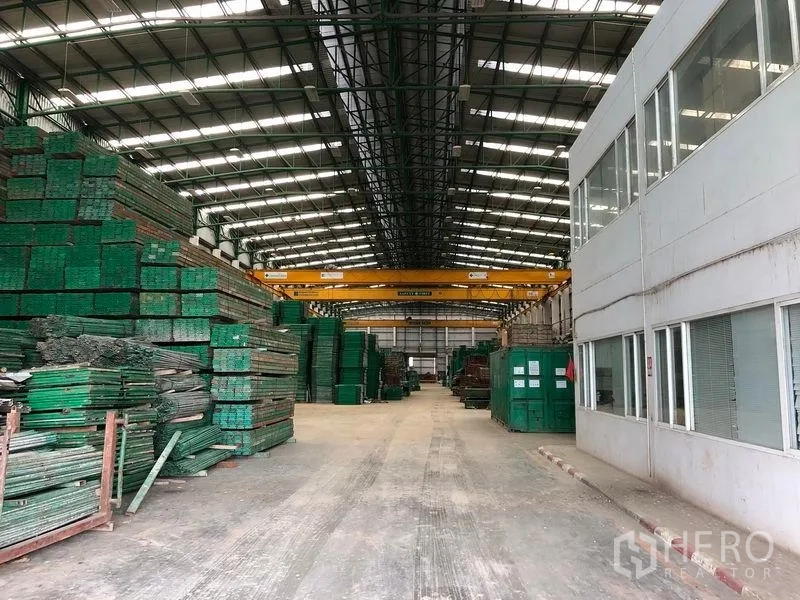 工厂 出租或出售在Lat Lum Kaeo, Pathum Thani - 办公室一侧的仓库通道，材料堆放与行车吊清晰可见。