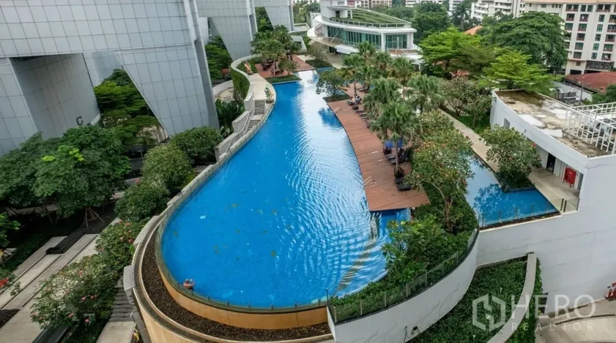 คอนโด ให้เช่าหรือขายในKhlong Toei, Bangkok - มุมสูงสระว่ายน้ำทรงโค้งสไตล์รีสอร์ทพร้อมดาดฟ้าไม้และสวนร่มรื่นของคอนโดในกรุงเทพฯ