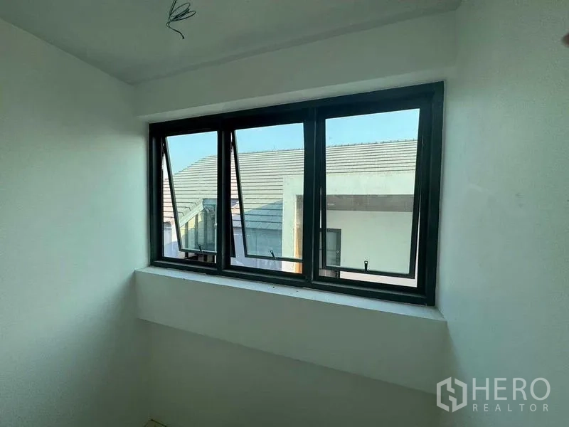 Home Office for rent in Don Mueang, Bangkok - Small room with three-pane casement window facing nearby rooftops.