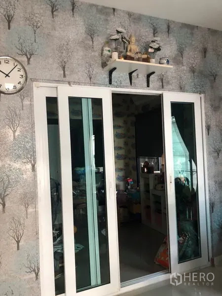 Townhouse for sale in Phasi Charoen, Bangkok - White-framed sliding glass doors with wall shelf and clock detail.