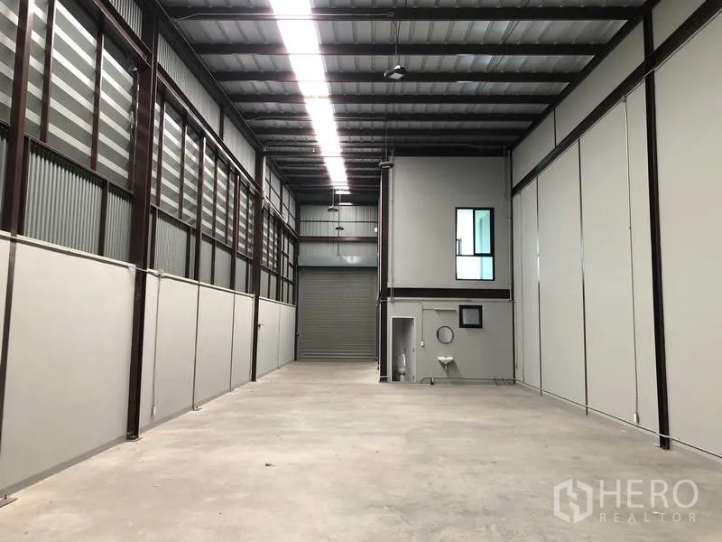 货栈 出租在Bang Phli, Samut Prakan - 仓库通道望向卷闸门，内置卫生间与高天花照明。