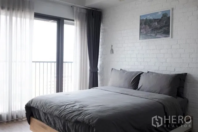 公寓 出租在Khlong Toei, Bangkok - 明亮卧室，灰色床品，落地窗与窗帘，连接阳台视野。