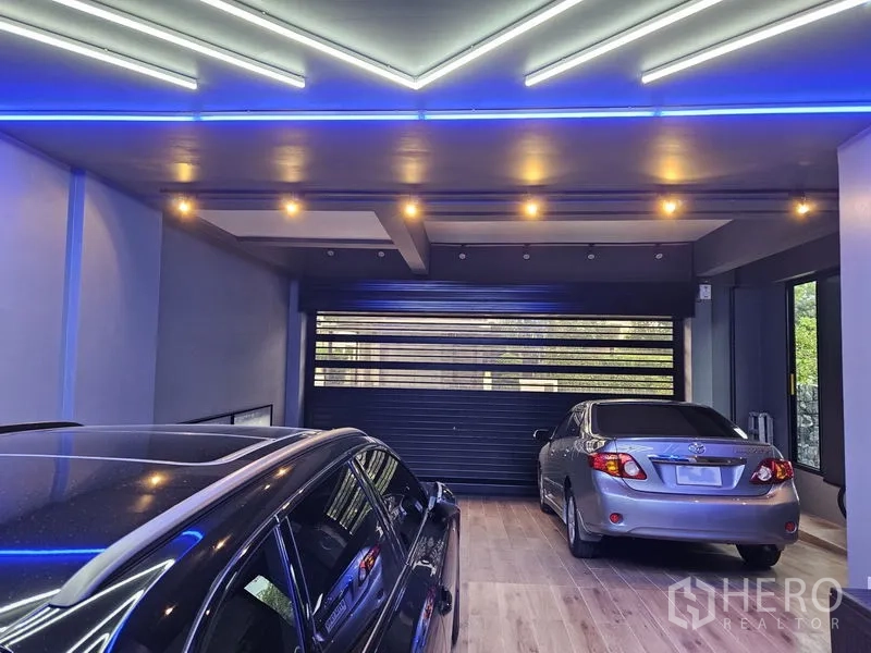 Detached House for sale in Thawi Watthana, Bangkok - Covered garage for multiple cars with LED strip lighting and roller door.