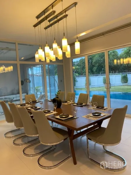 บ้าน ให้เช่าในSuan Luang, Bangkok - ห้องรับประทานอาหารร่วมสมัย โต๊ะยาว โคมไฟแขวน มองเห็นสระผ่านประตูกระจกบานเลื่อน
