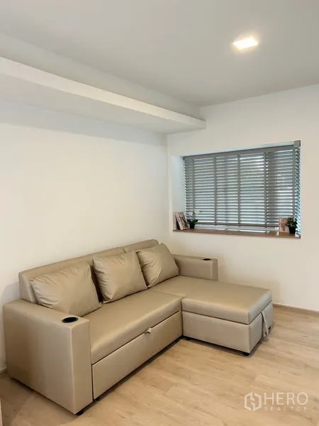 ทาวน์เฮาส์ ให้เช่า - มุมนั่งเล่นอบอุ่น โซฟาหนังทรง L ข้างหน้าต่างพร้อมมู่ลี่.