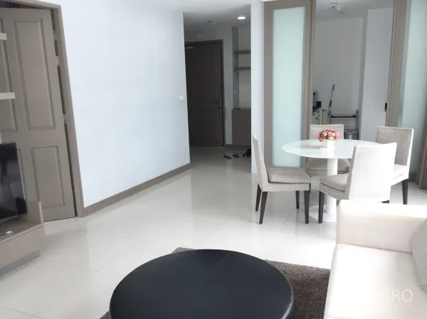 คอนโด ให้เช่าในPathum Wan, Bangkok - มุมห้องนั่งเล่นพร้อมทีวี โต๊ะกินข้าวหินอ่อน และประตูสไลด์ไปยังครัว