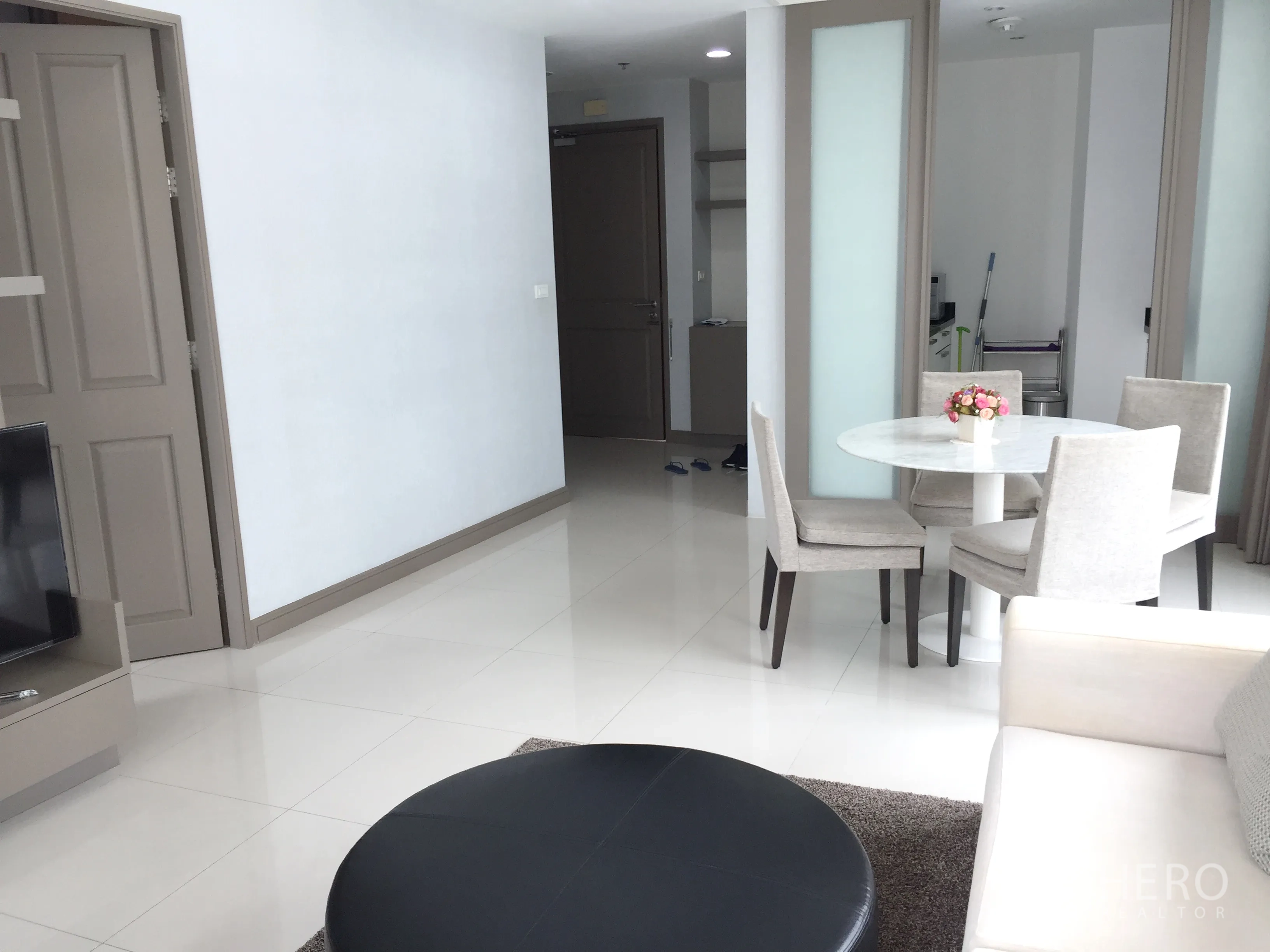 คอนโด ให้เช่าในPathum Wan, Bangkok - มุมห้องนั่งเล่นพร้อมทีวี โต๊ะกินข้าวหินอ่อน และประตูสไลด์ไปยังครัว