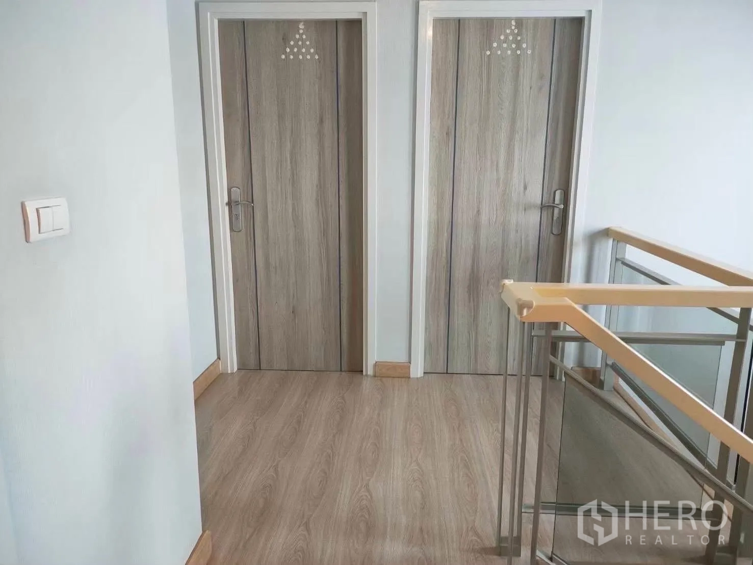 บ้านเดี่ยว for rent in Bang Phli, Samut Prakan - โถงชั้นบนพื้นลายไม้ มีประตูสองบานและราวบันไดกระจกกับโครงเหล็ก