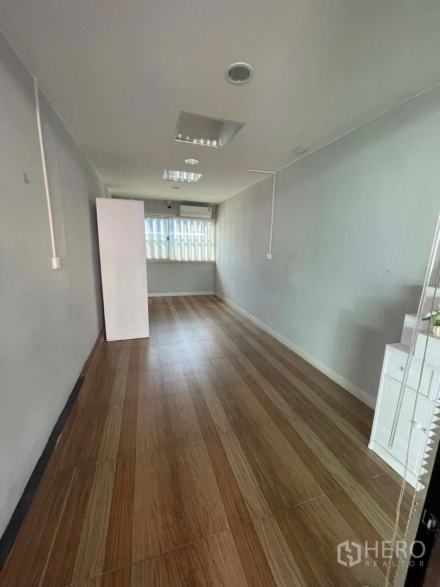 Detached House for rent or sale in Lam Luk Ka, Pathum Thani - Long narrow multipurpose room with wood-look flooring and air conditioning.