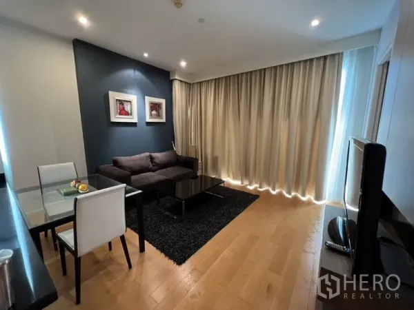 公寓 出租在Chatuchak, Bangkok - 舒适起居区，玻璃电视柜、大窗帘与厨房吧台旁的用餐角落。