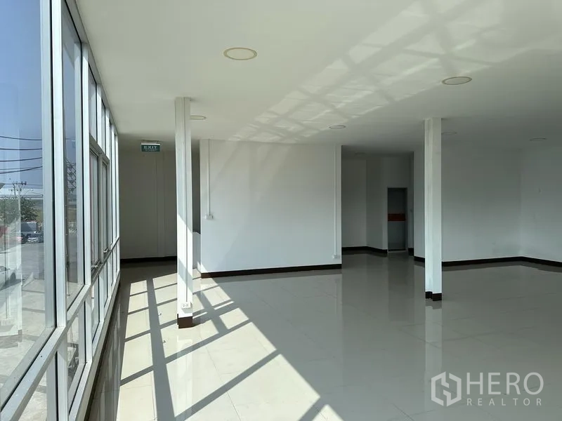 Warehouse for rent in Samut Prakan - Sunlit office corridor with floor-to-ceiling windows and white walls.