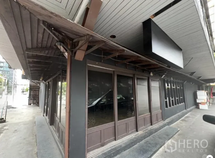 พื้นที่ขายปลีก ให้เช่าในWatthana, Bangkok - ด้านหน้ามุมพื้นที่ค้าปลีกชั้นล่าง หลังคาไม้สีเข้มและผนังกระจกเต็มบาน