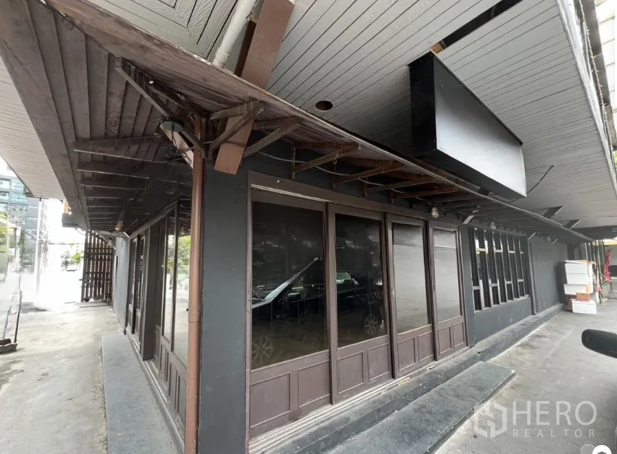 พื้นที่ขายปลีก ให้เช่าในWatthana, Bangkok - ด้านหน้ามุมพื้นที่ค้าปลีกชั้นล่าง หลังคาไม้สีเข้มและผนังกระจกเต็มบาน