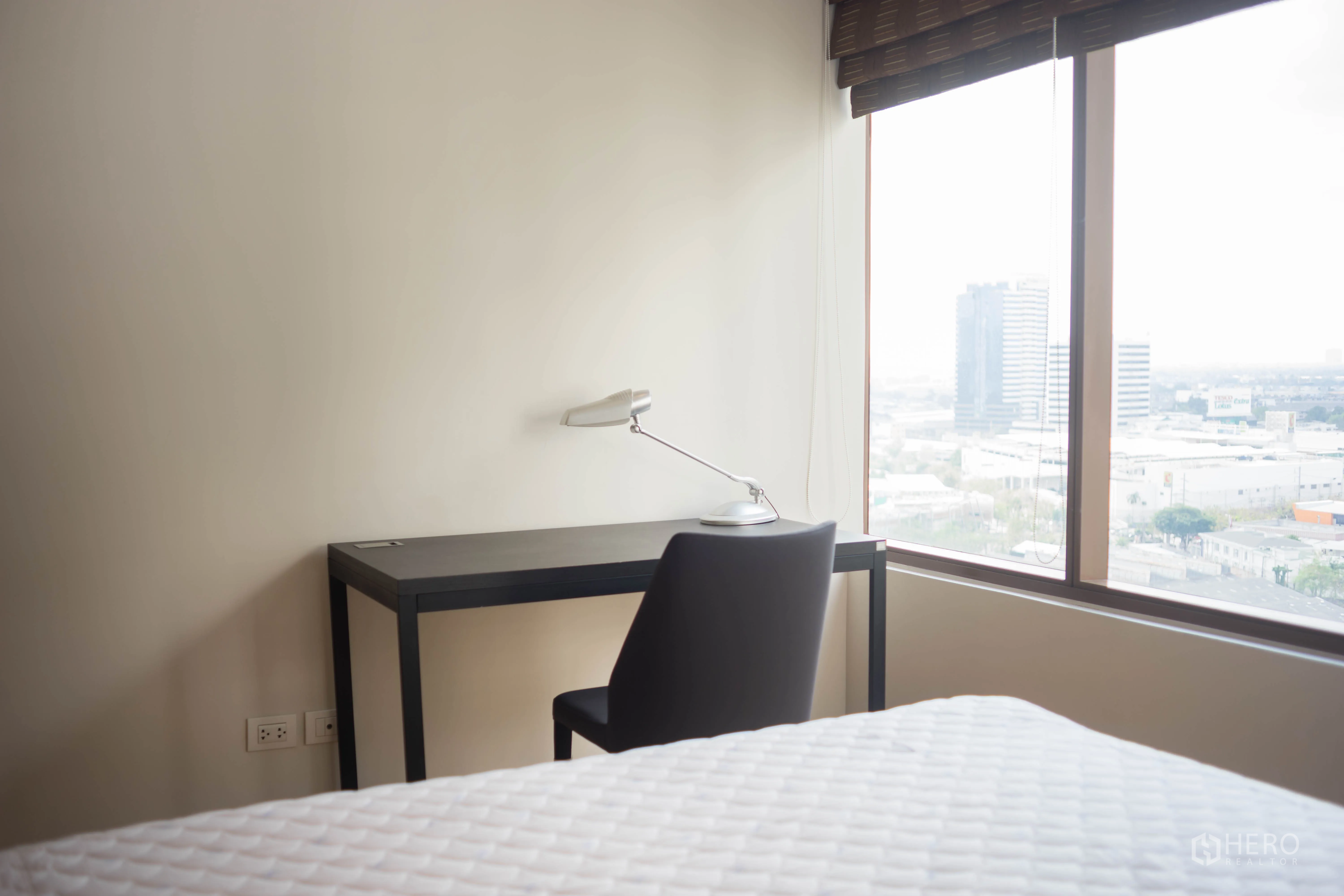Condominium for rent or sale in Khlong Toei, Bangkok - Compact study nook with desk, chair and lamp beside a large window with city views.