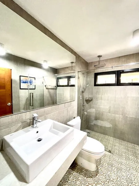 Townhouse for rent in Khlong Toei, Bangkok - Modern bathroom with large mirror, rain shower and patterned floor tiles.