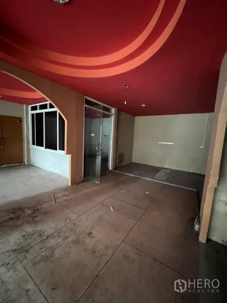 店屋 出租在Watthana, Bangkok - 一层室内，红色弧形天花与玻璃隔间，水泥地面待装修。