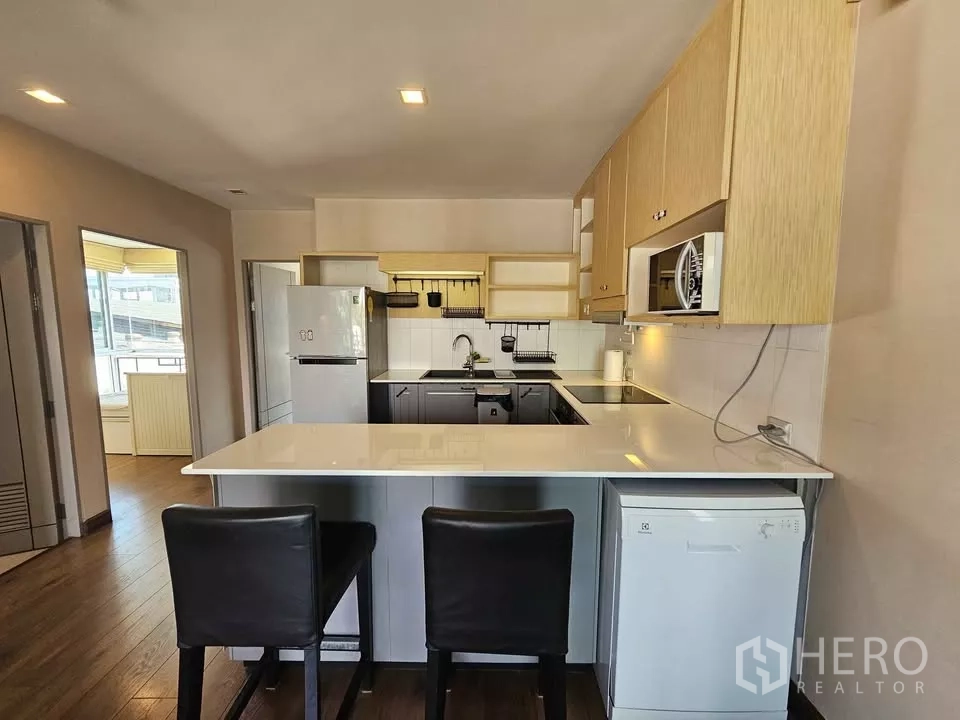 公寓 出售在Phra Khanong, Bangkok - 厨房正面视角，白色台面、冰箱与洗碗机。