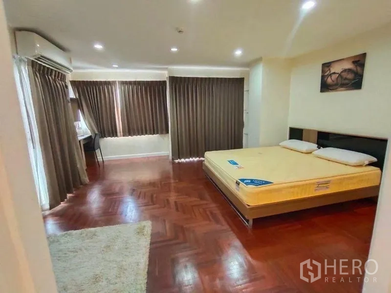 Condominium for rent or sale in Bang Rak, Bangkok - Spacious master bedroom with wood floors, large windows, and a study desk.
