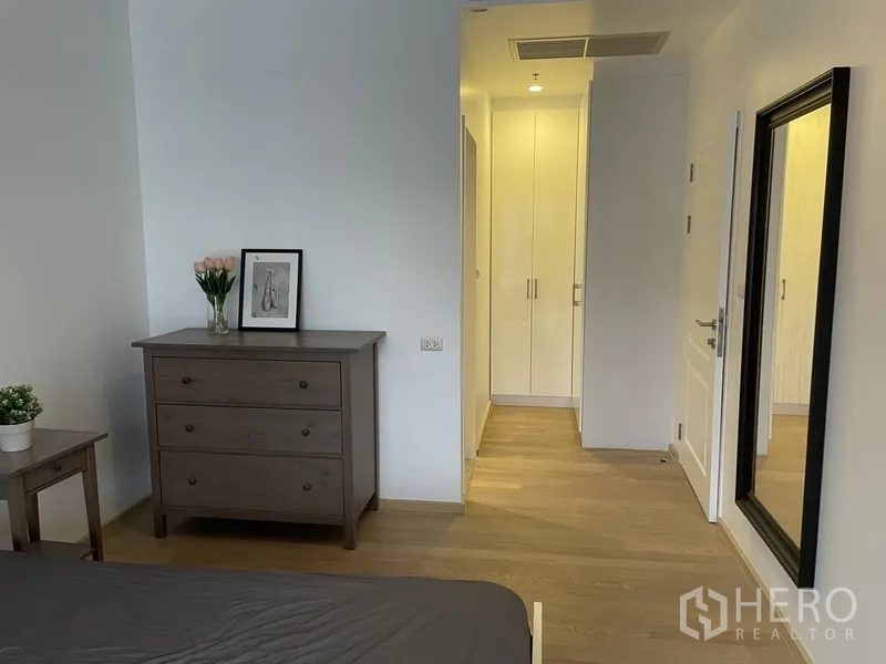 公寓 出租在Bangkok - 卧室一角，带五斗柜、全身镜和衣柜。