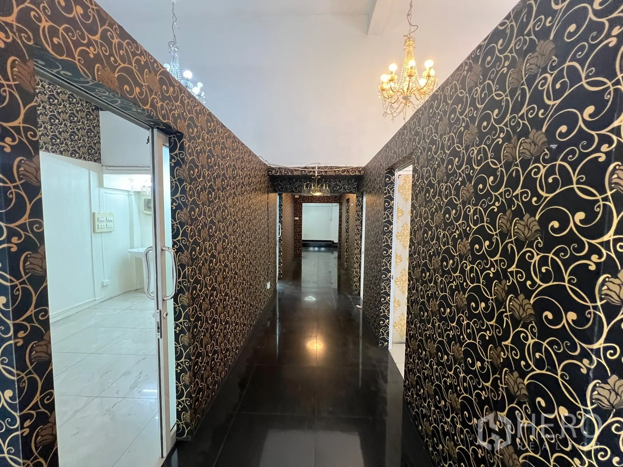 อาคารพาณิชย์ ให้เช่าในKhlong Toei, Bangkok - โถงทางเดินวอลเปเปอร์สีดำทอง มีโคมระย้าต่อเนื่องสู่ห้องด้านหลัง