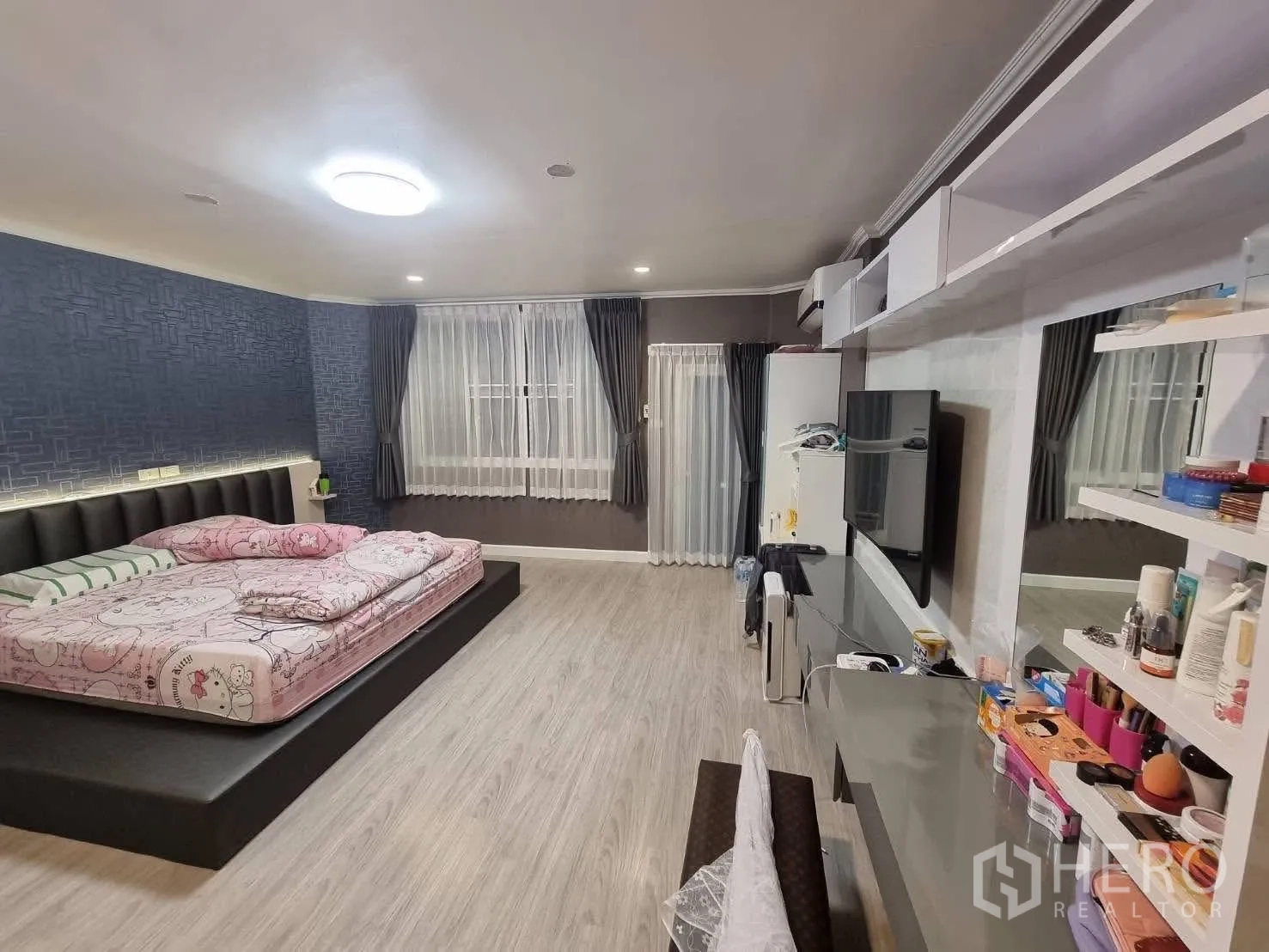 Townhouse for rent in Din Daeng, Bangkok - Expansive bedroom with platform bed, TV, shelves and sliding door curtains.