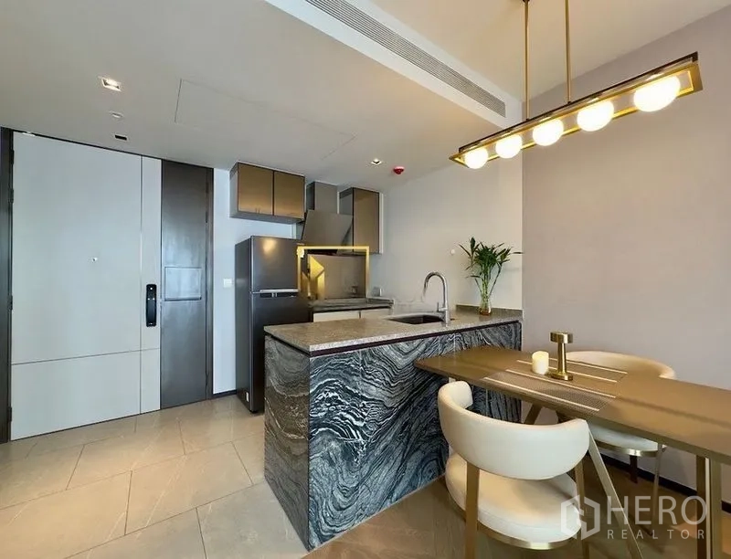 公寓 for rent or sale in Watthana, Bangkok - 现代厨房，纹理石材中岛、冰箱与吊灯下的餐桌。