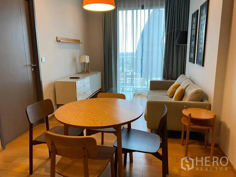 คอนโด ให้เช่าในKhlong Toei, Bangkok - พื้นที่นั่งเล่นและรับประทานอาหารแบบโอเพ่น พร้อมโต๊ะไม้ทรงกลม โซฟา และประตูกระจกออกระเบียง